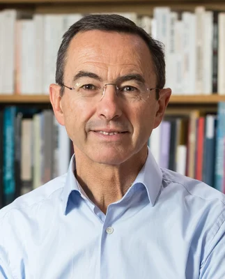 Portrait de Bruno Retailleau portant une chemise bleue clair devant des étagères de livres.