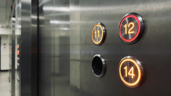 Panneau d'ascenseur d'hôtel avec les boutons 11, 12 et 14, le chiffre 13 manquant, éclairage tamisé