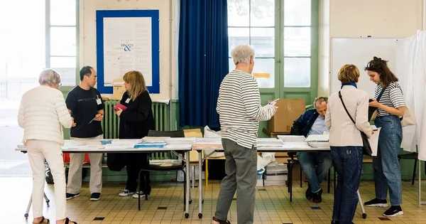 Scène d'un bureau de vote avec des électeurs et des assesseurs lors d'une élection.