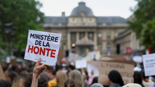Une manifestante brandit une pancarte 'ENFANCE BRISÉE JUSTICE REFUSÉE' lors d'un rassemblement contre les violences sexuelles.