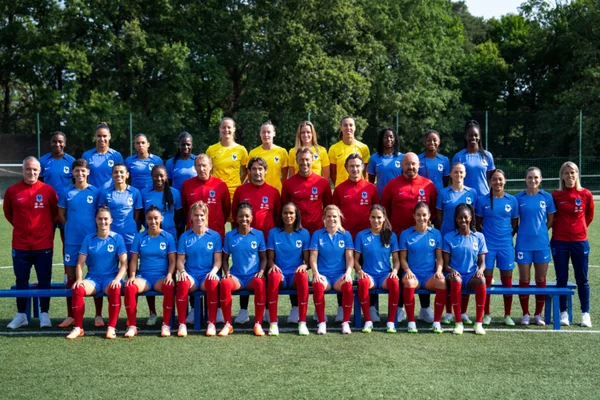 Photo de groupe des Bleues en tenue d'entraînement sur un terrain synthétique.