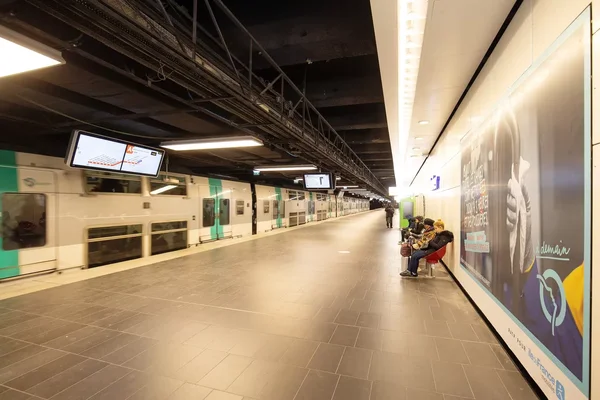 Un train RER A à l'arrêt sur un quai de station, avec des voyageurs attendant sur un banc.