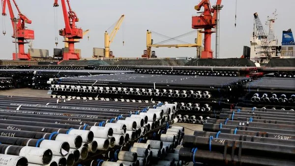 Port industriel avec stocks de tubes d'acier et grues de manutention.