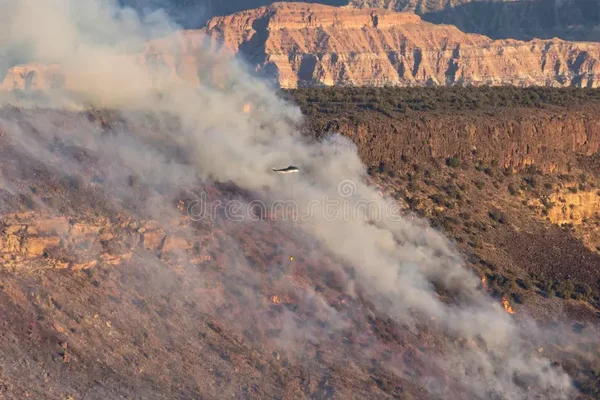 Hélicoptère survolant un incendie de forêt dans l'Utah, larguant de l'eau ou un retardateur sur les flammes.