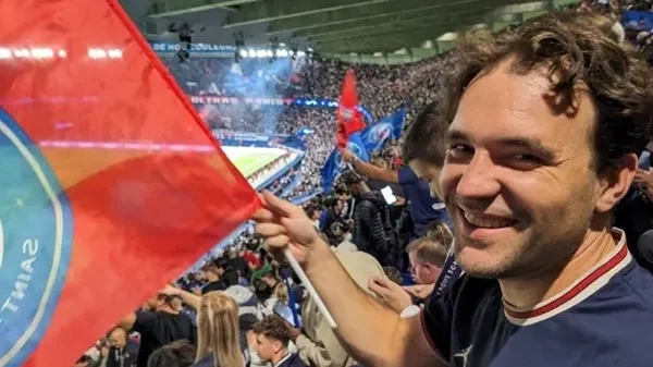Un supporter brandissant un drapeau rouge dans un stade animé lors d'un match.