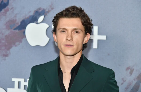Tom Holland en costume vert foncé, devant le logo Apple TV+.
