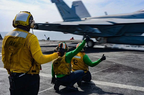 Personnel de pont guidant un chasseur sur le porte-avions américain.