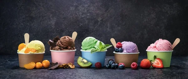 Assortiment de glaces en coupe, présentées avec fruits et garnitures.