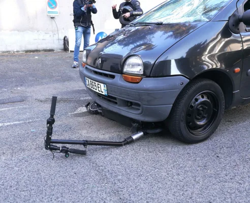 Dispositif de blocage de trottinette attaché à une fourgonnette lors d'un crash-test, illustrant les mesures de sécurité.