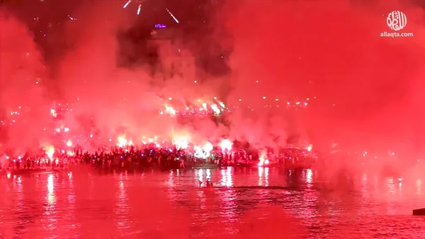 Supporters du Mouloudia rassemblés sur le front de mer, illuminant la nuit de rouge.