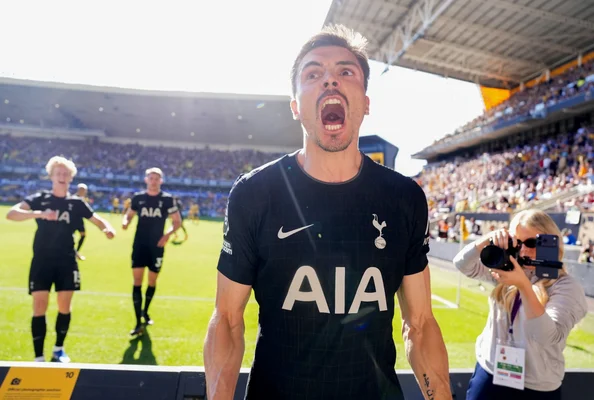 Un joueur de Tottenham Hotspur célébrant un but, maillot noir, entouré de coéquipiers.