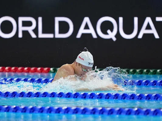 Léon Marchand lors d'une course de 200 m brasse, avec le panneau World Aquatics en arrière-plan.