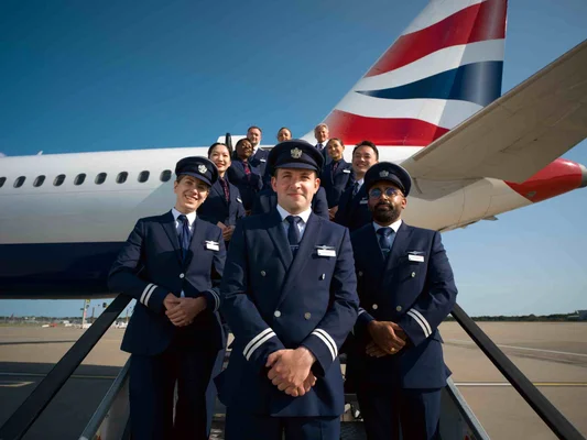 Pilotes et personnel de cabine de British Airways posant sur la passerelle d'un avion de la compagnie.
