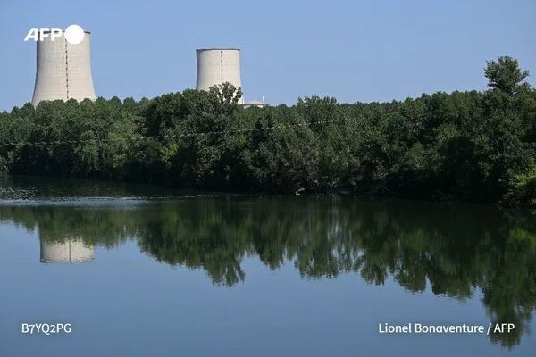 Centrale nucléaire reflétée dans l'eau, symbole des arrêts de réacteurs dus à la canicule.
