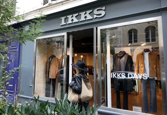 Une passante observe la vitrine d'un magasin IKKS, symbole des difficultés du prêt-à-porter.