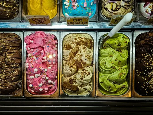 Comptoir de glaces italiennes montrant différents parfums en bacs.