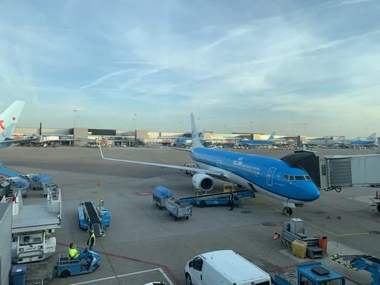 Un Boeing 737 de KLM à l'aéroport d'Amsterdam Schiphol, avec passerelle et équipements au sol.