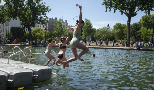 Trois femmes sautant dans l'eau d'un site de baignade parisien.