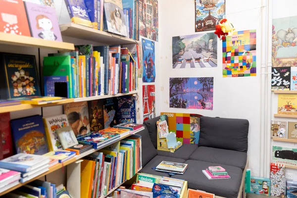 Epace lecture jeunesse dans une librairie indépendante, avec canapé et affiches colorées.