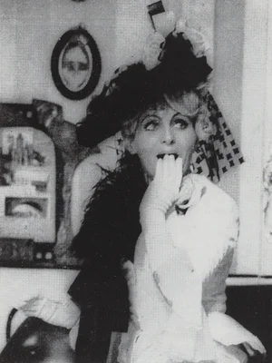 Nicole Croisille en costume de scène théâtral, chapeau à plumes et gants longs.