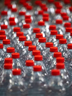Bouteilles en plastique à bouchon rouge, illustrant le débat sur la consigne.