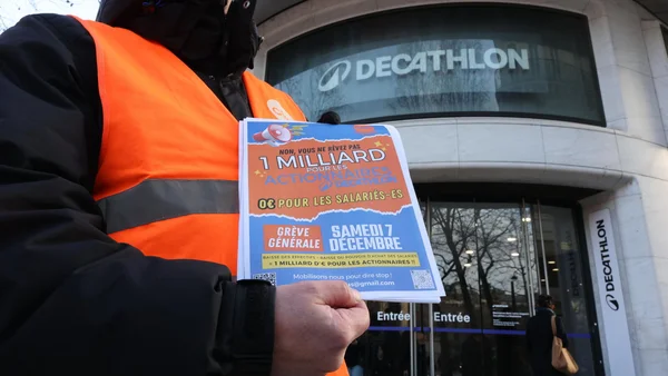 Un salarié proteste devant un magasin Decathlon avec un tract dénonçant le partage de la valeur.