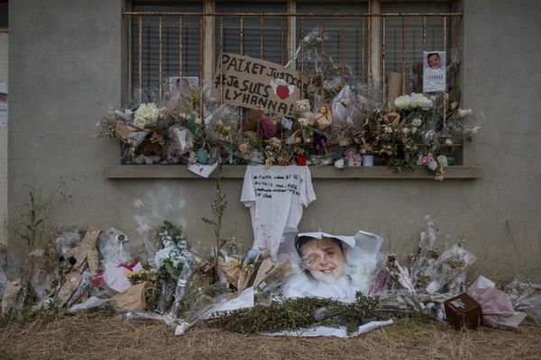 Hommage floral et messages rendus à Lyhanna devant un bâtiment.
