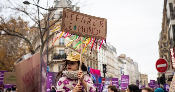 Enfant manifestant avec pancarte 'Réparer le monde' lors d'un rassemblement pour les droits des femmes et des enfants