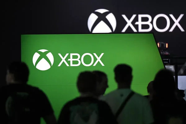 Événement Xbox avec des silhouettes devant un écran vert affichant le logo