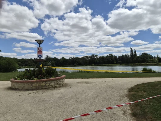 Ruban de signalisation jaune dans un parc parisien, illustrant les recherches en cours.