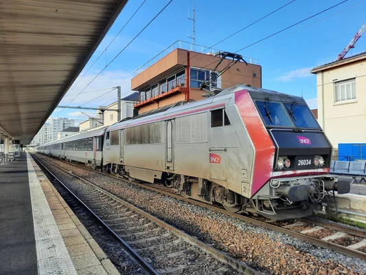 Locomotive électrique SNCF 26034 tractant un train de voyageurs en gare.