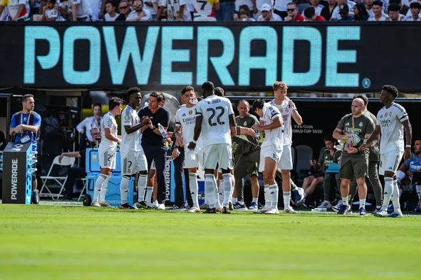 Joueurs du Real Madrid lors d'une pause, avec un panneau publicitaire Powerade en arrière-plan.