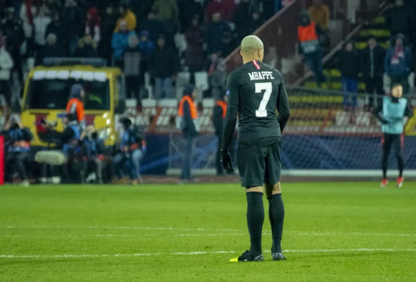 Kylian Mbappé sur la pelouse lors d'un match, arborant le maillot noir numéro 7.