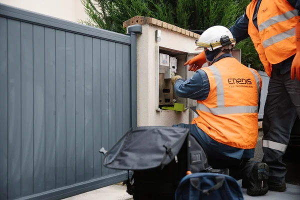 Techniciens Enedis réparent un coffret électrique en période de canicule.