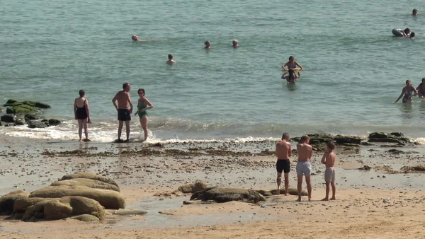 Des vacanciers profitent de la fraîcheur des côtes de la Manche en Bretagne pour se baigner et se détendre sur la plage.