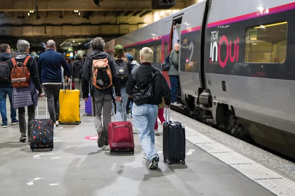 Des voyageurs se dirigeant vers un TGV inOui sur le quai d'une gare.