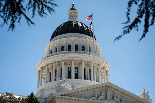 Le dôme blanc du Capitole d'État californien sous un ciel bleu, vu en contre-plongée.