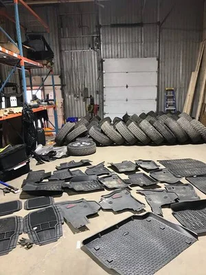 Intérieur d'un entrepôt contenant des tapis de sol et des pneus usagés.