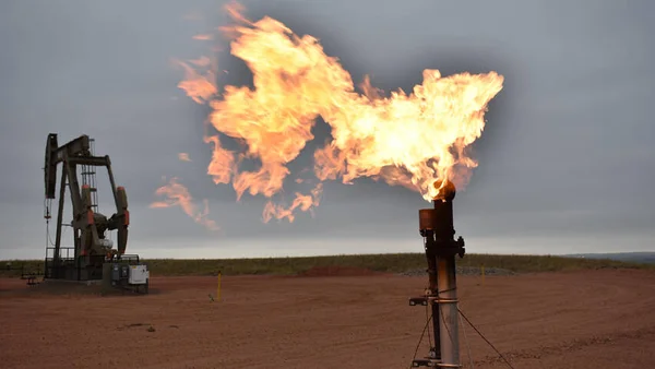 Torche de gaz et pompe à balancier sur un champ pétrolier.
