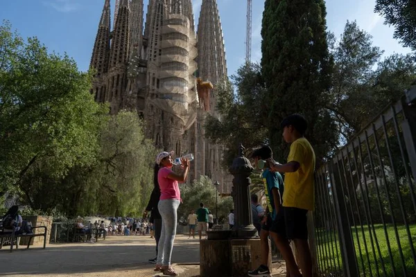 Des touristes visitent Barcelone sous une chaleur accablante, avec la Sagrada Familia en toile de fond, alors que l'alerte rouge canicule est déclenchée en Italie et en Espagne.
