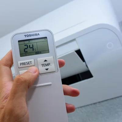 Télécommande de climatisation réglée à 24°C, symbole des débats politiques sur la clim.