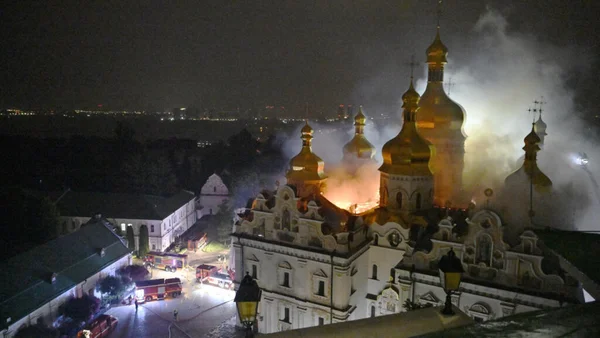 Église orthodoxe en feu à Kiev après des frappes russes, vue nocturne avec intervention des pompiers.