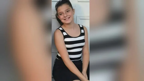 Lyhanna, jeune fille souriante, photographiée devant une porte blanche.