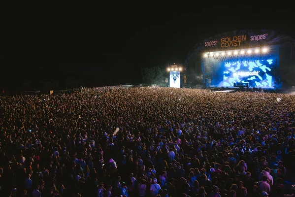 Foule massive au Golden Coast Festival, sous les lumières bleues de la scène principale.