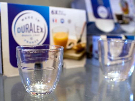 Un verre Duralex posé sur une surface réfléchissante, avec son emballage d'origine.