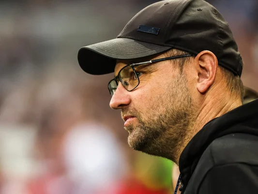 Mathieu Bodmer en tenue décontractée, casquette noire, arrière-plan de stade.