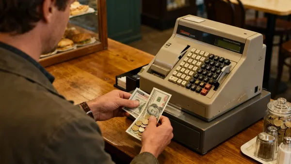 Client payant en espèces dans un café, illustrant les habitudes de paiement traditionnelles.