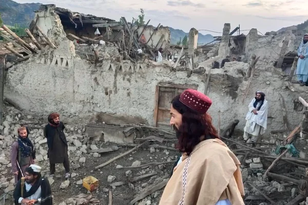 Des hommes évaluent les dégâts dans les ruines d'un bâtiment en terre effondré.