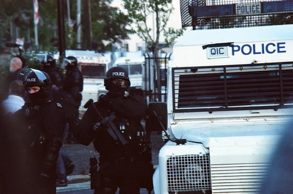 Officiers du PSNI en tenue anti-émeute lors des émeutes de Belfast en 2011, avec un véhicule blindé.