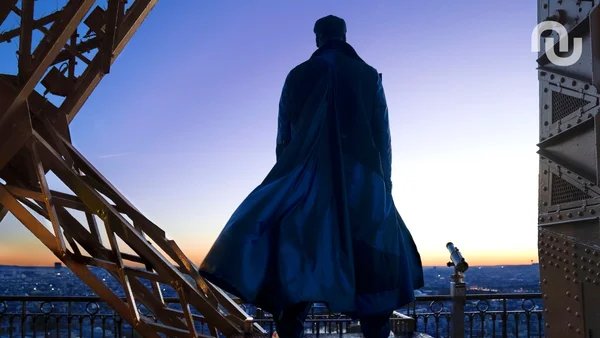 Vue de dos d'un personnage en manteau sur une plateforme d'observation, possible scène de Lupin saison 4.